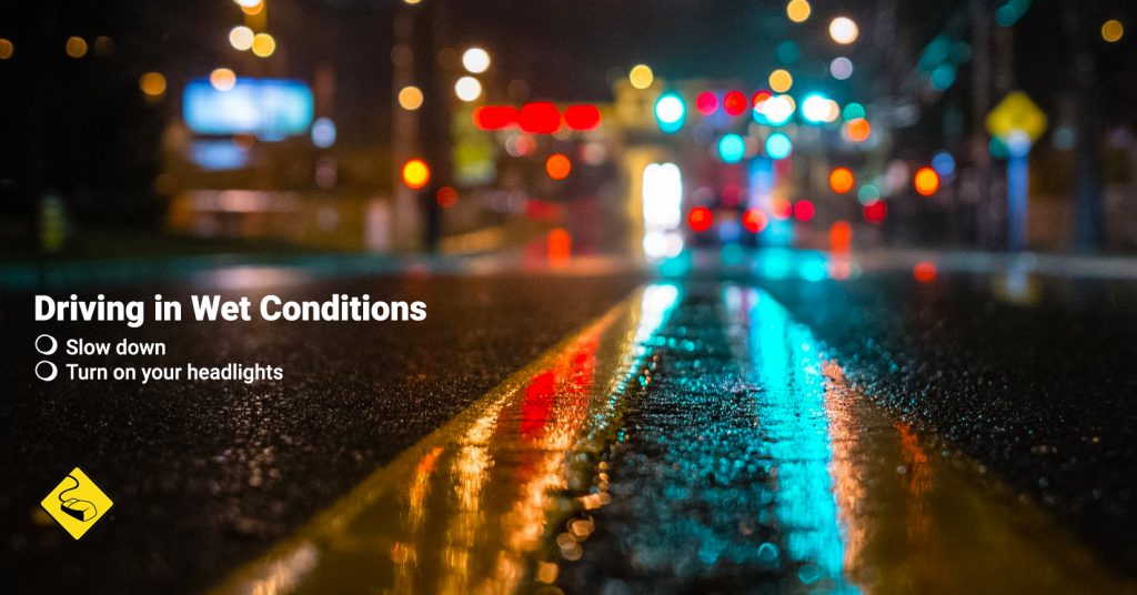 wet road with yellow road lines and lights in the distance